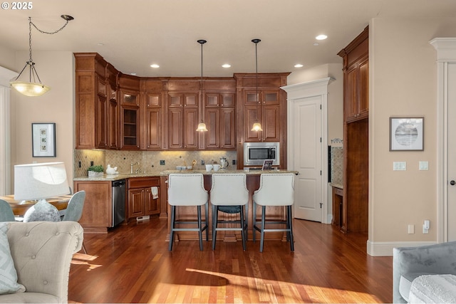 kitchen featuring a kitchen island, stainless steel microwave, decorative light fixtures, decorative backsplash, and light stone countertops