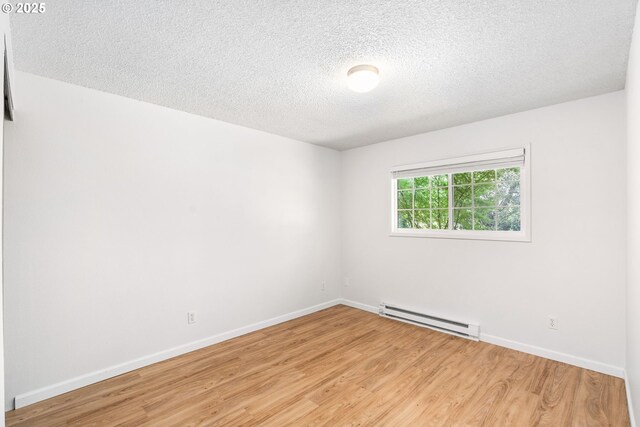 6654 SW Capitol Hwy, Portland, OR 97219 - empty room with baseboard heating, light wood-type flooring, a textured ceiling, and baseboards