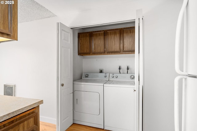 6654 SW Capitol Hwy, Portland, OR 97219 - washroom featuring washing machine and dryer, light wood-type flooring, and cabinet space