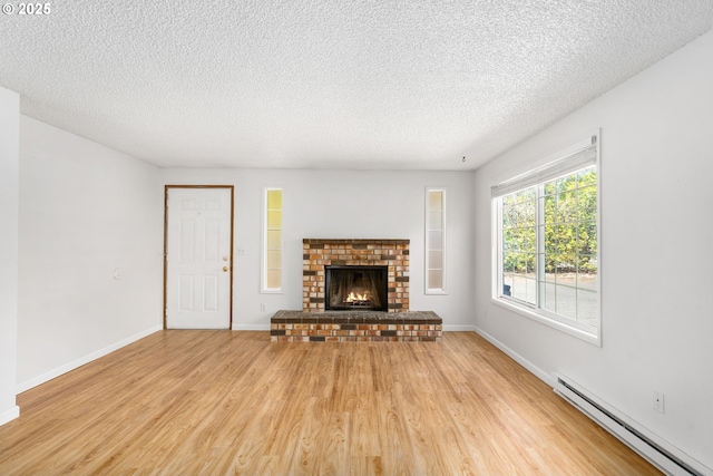 6654 SW Capitol Hwy, Portland, OR 97219 - unfurnished living room featuring a baseboard radiator, light wood-style floors, a textured ceiling, baseboards, and a fireplace