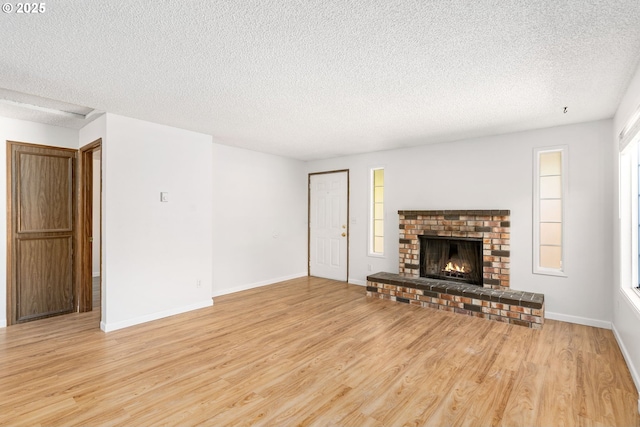 6654 SW Capitol Hwy, Portland, OR 97219 - unfurnished living room featuring wood finished floors, a textured ceiling, a brick fireplace, and baseboards