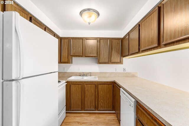 6654 SW Capitol Hwy, Portland, OR 97219 - kitchen with white appliances, a sink, brown cabinetry, and light countertops