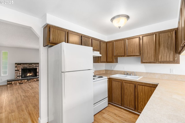 6654 SW Capitol Hwy, Portland, OR 97219 - kitchen with white appliances, a sink, light countertops, under cabinet range hood, and light wood-style flooring