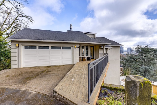 view of front facade with an attached garage, roof with shingles, and driveway