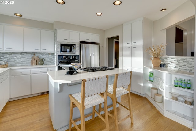 kitchen with black appliances, light wood-style flooring, white cabinets, and a kitchen island