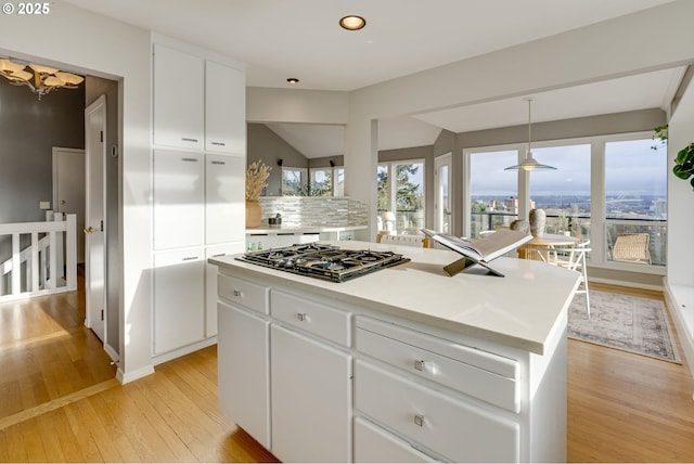 kitchen featuring light wood-type flooring, a center island, gas stovetop, white cabinets, and decorative backsplash