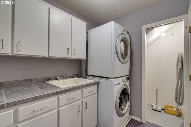 laundry room featuring stacked washer / dryer, cabinet space, and a sink