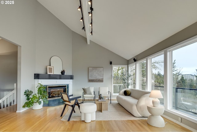 living room with baseboards, high vaulted ceiling, wood finished floors, and a tile fireplace