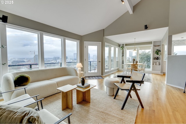 living area featuring baseboards, high vaulted ceiling, light wood-style floors, a city view, and beamed ceiling