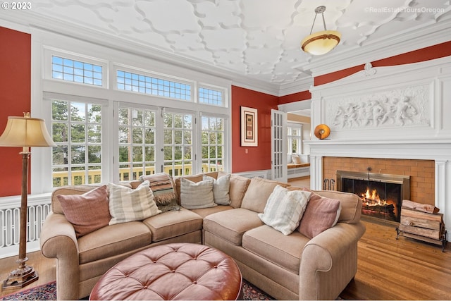 living room with a brick fireplace, hardwood / wood-style floors, and crown molding