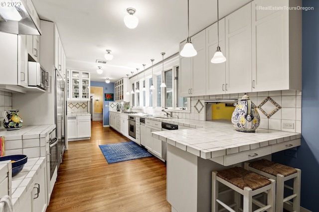 kitchen with sink, white cabinetry, a kitchen breakfast bar, light hardwood / wood-style flooring, and decorative backsplash