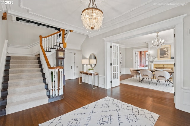 entrance foyer with dark wood-type flooring, an inviting chandelier, and crown molding