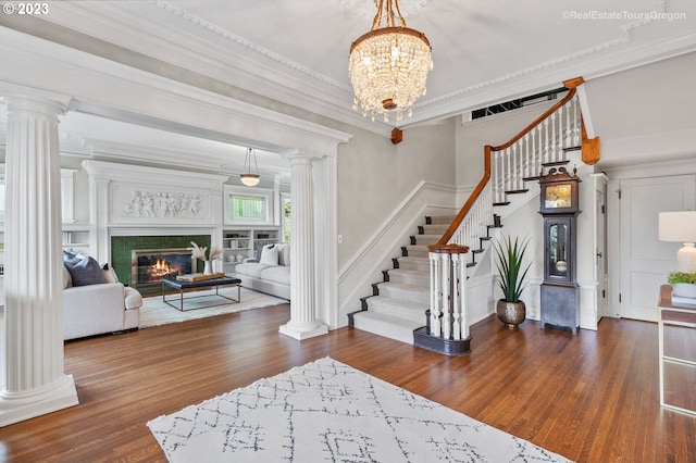 foyer entrance with dark wood-type flooring, a tile fireplace, crown molding, and a chandelier