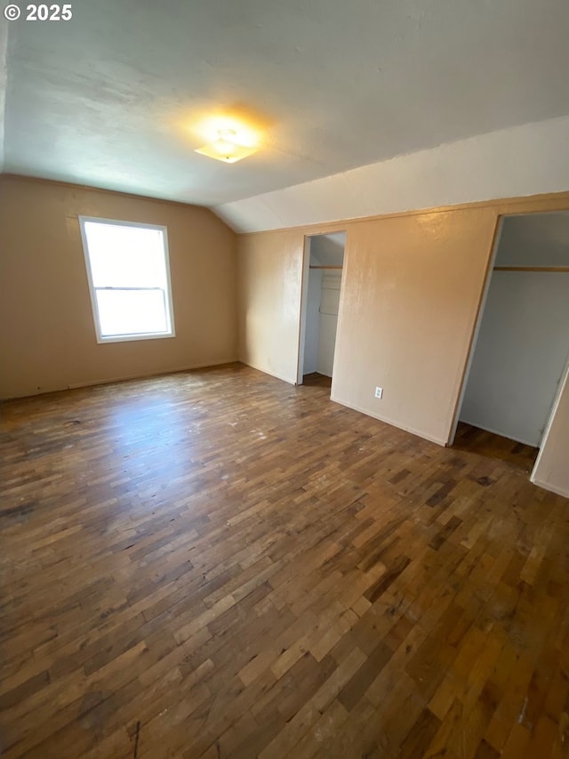 unfurnished room featuring lofted ceiling and dark wood-type flooring