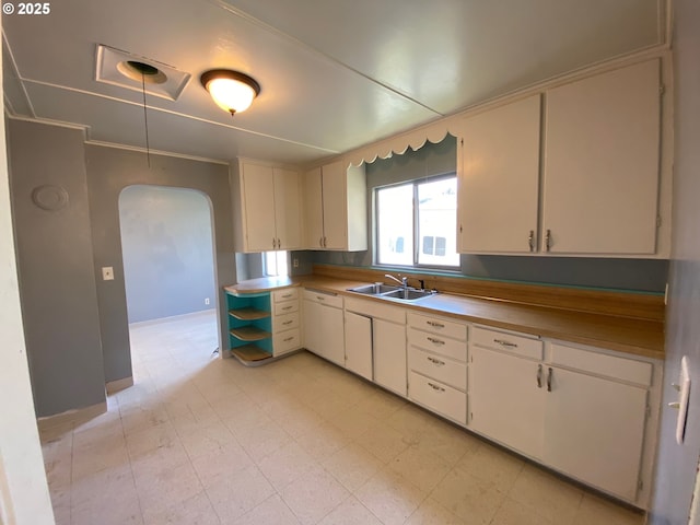 kitchen with sink, white cabinets, and ornamental molding