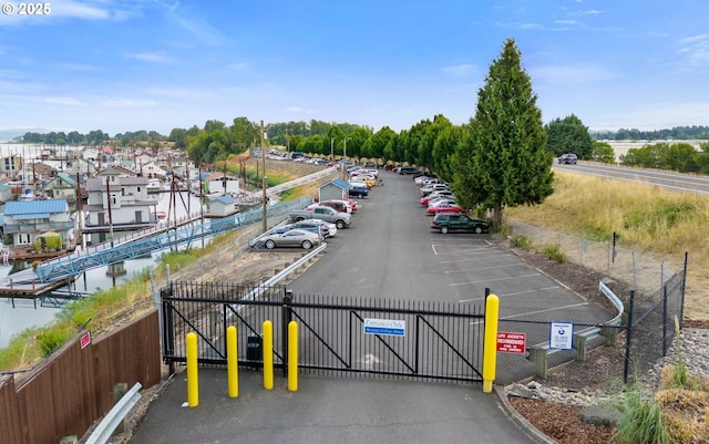 uncovered parking lot featuring a gate and fence