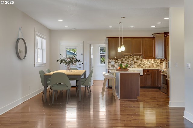 427 NW Garibaldi St, Hillsboro, OR 97124 - kitchen featuring a kitchen island, light countertops, decorative backsplash, stainless steel stove, and baseboards