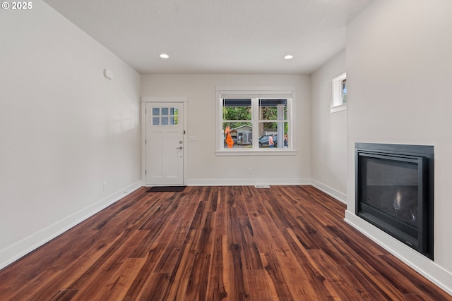 427 NW Garibaldi St, Hillsboro, OR 97124 - unfurnished living room featuring a glass covered fireplace, dark wood-style flooring, baseboards, and recessed lighting