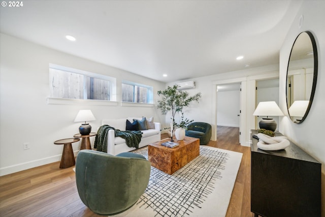 living room with a wall mounted AC and light wood-type flooring