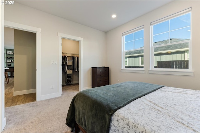 bedroom with baseboards, a walk in closet, carpet flooring, a closet, and recessed lighting