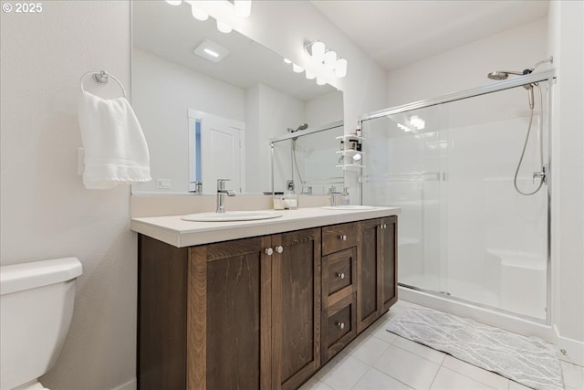 bathroom featuring double vanity, a stall shower, a sink, and toilet