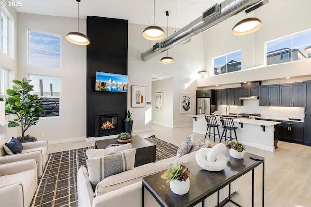 living area featuring light wood finished floors, baseboards, and a glass covered fireplace