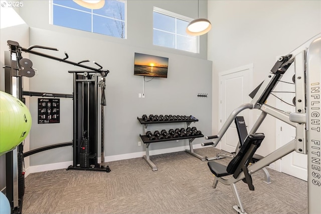 workout room with a high ceiling, carpet flooring, and baseboards