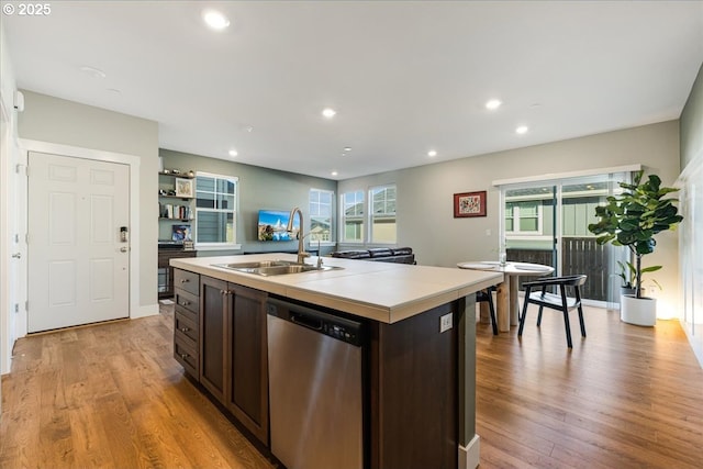 kitchen with a sink, dark brown cabinets, light countertops, dishwasher, and light wood finished floors