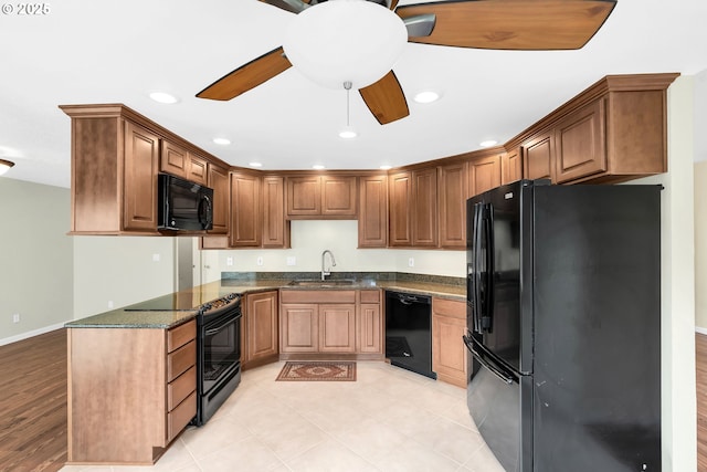 kitchen with black appliances, a sink, a ceiling fan, recessed lighting, and dark stone counters