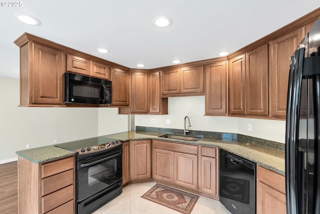kitchen featuring black appliances, a sink, recessed lighting, and dark stone countertops