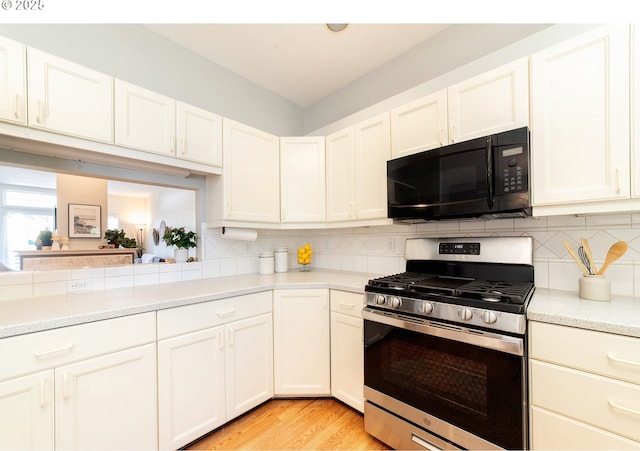 3540 S Corbett Ave, Portland, OR 97239 - kitchen with black microwave, gas range, light countertops, and backsplash