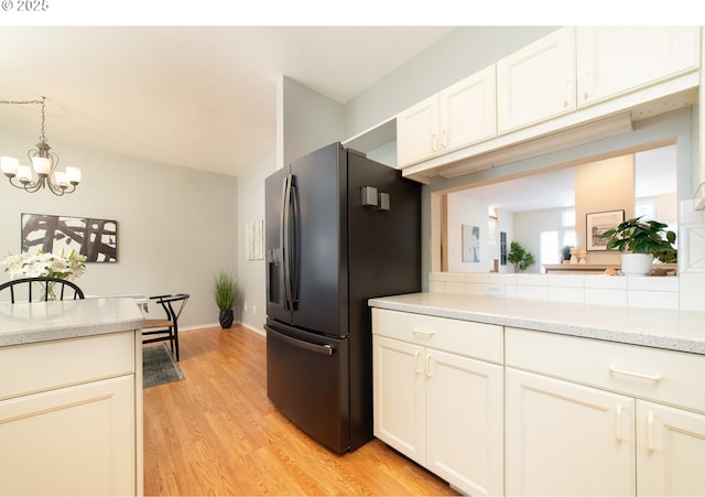 3540 S Corbett Ave, Portland, OR 97239 - kitchen with refrigerator with ice dispenser, a chandelier, light wood finished floors, white cabinetry, and decorative light fixtures
