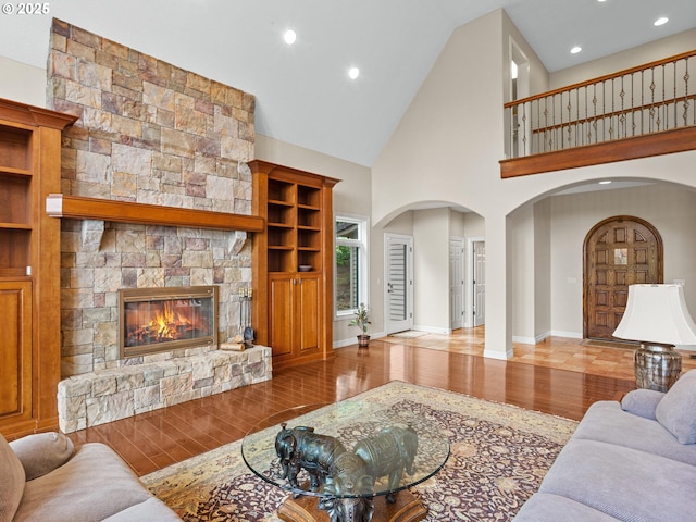 8801 SE Walnut Dr, Amity, OR 97101 - living room featuring arched walkways, wood finished floors, a stone fireplace, recessed lighting, and high vaulted ceiling