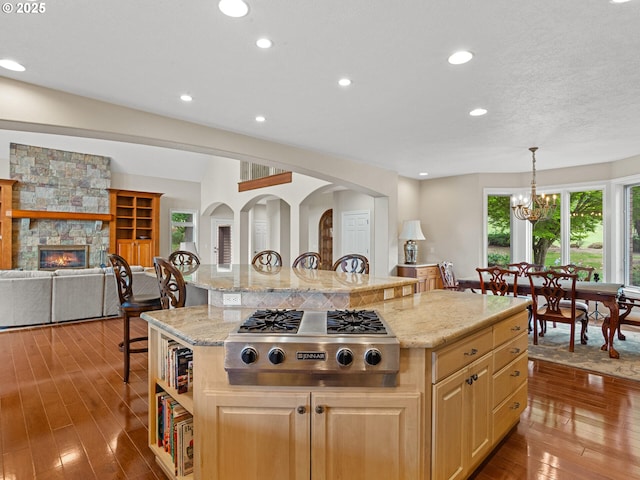 8801 SE Walnut Dr, Amity, OR 97101 - kitchen with stainless steel gas stovetop, a center island, wood finished floors, a stone fireplace, and recessed lighting