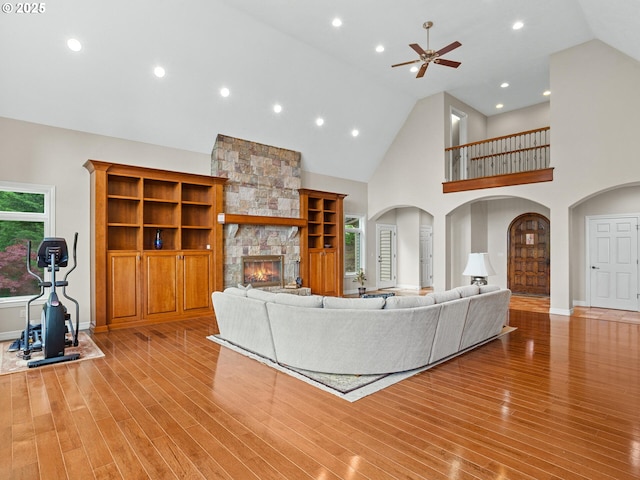 8801 SE Walnut Dr, Amity, OR 97101 - living area featuring arched walkways, ceiling fan, a fireplace, light wood-style flooring, and high vaulted ceiling