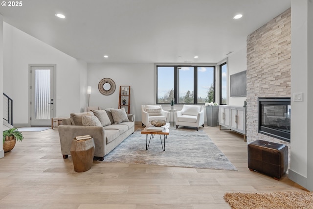 living room featuring a stone fireplace and light wood-type flooring