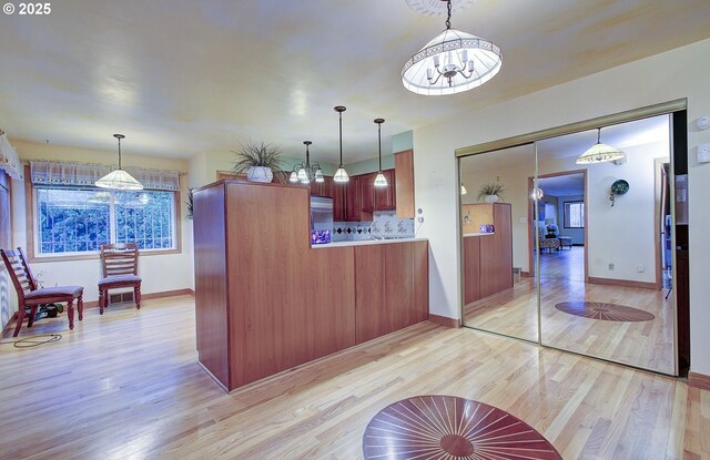 kitchen with pendant lighting, light wood-style flooring, stainless steel refrigerator, plenty of natural light, and light countertops