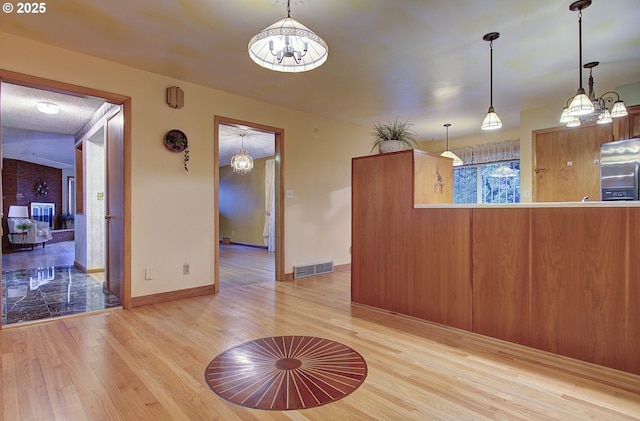 interior space featuring visible vents, pendant lighting, freestanding refrigerator, and light wood-style floors