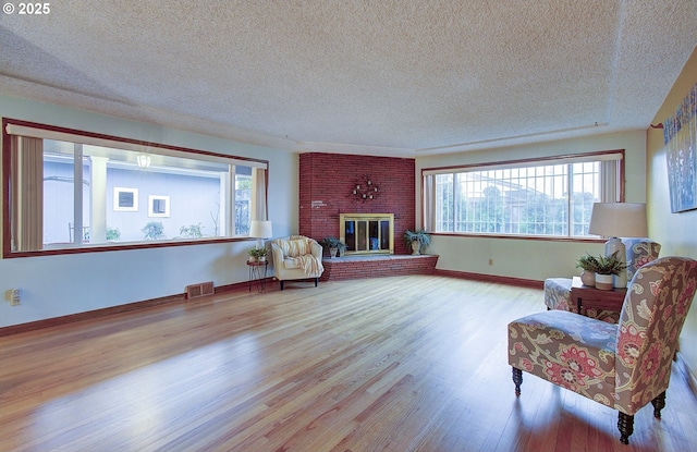 living area featuring visible vents, a fireplace, baseboards, and wood finished floors