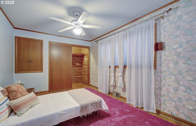 bedroom with visible vents, a textured ceiling, ornamental molding, and wallpapered walls