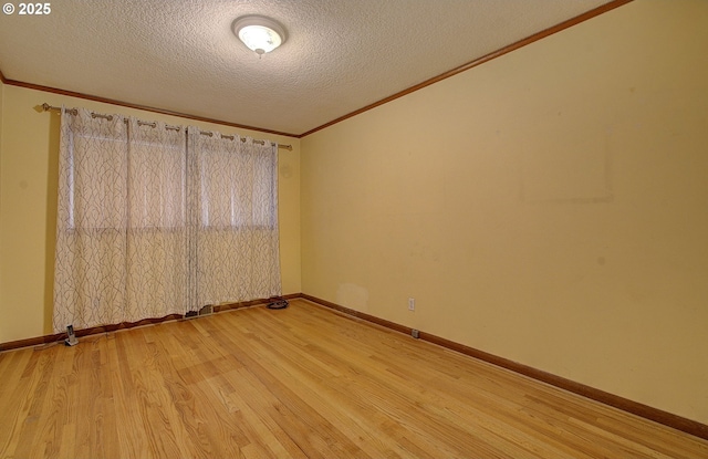 spare room with light wood-type flooring, baseboards, a textured ceiling, and crown molding