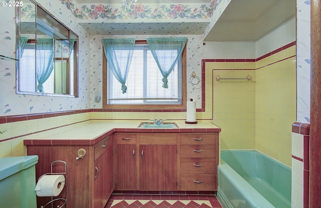 full bath featuring wallpapered walls, toilet, vanity, wainscoting, and tile walls