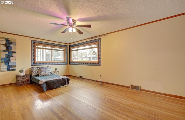 unfurnished bedroom with a textured ceiling, crown molding, visible vents, and light wood-type flooring