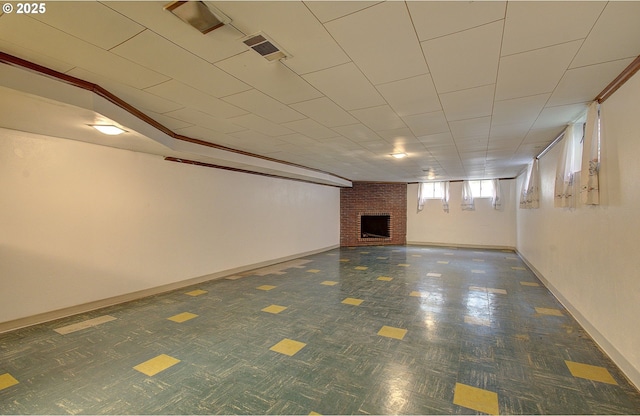 below grade area with visible vents, baseboards, and a brick fireplace