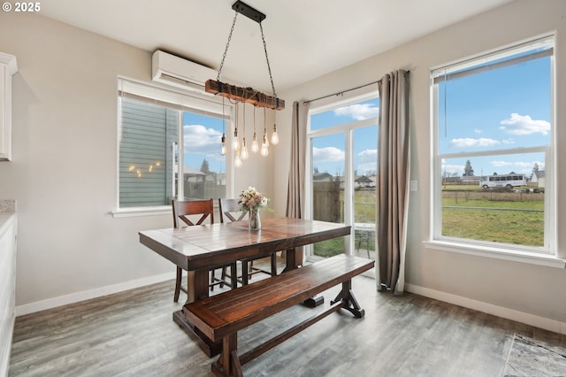 dining space with wood finished floors, baseboards, and a wall mounted AC