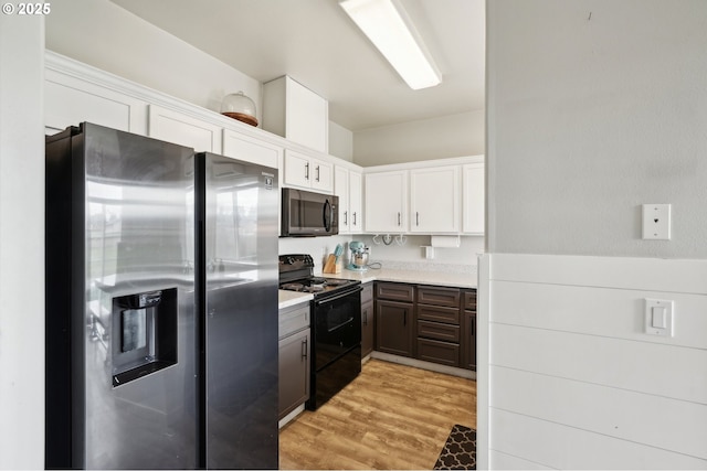 kitchen featuring black / electric stove, light wood-style flooring, white cabinets, light countertops, and stainless steel fridge