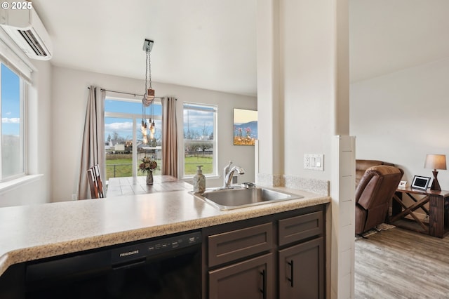 kitchen featuring light wood finished floors, dishwasher, a wall mounted air conditioner, light countertops, and a sink