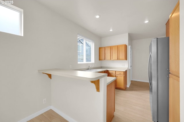 5298 Wales Dr, Eugene, OR 97402 - kitchen with freestanding refrigerator, a peninsula, baseboards, a kitchen bar, and light wood finished floors