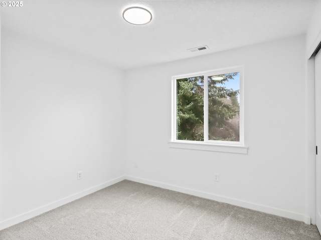 carpeted spare room with baseboards and visible vents