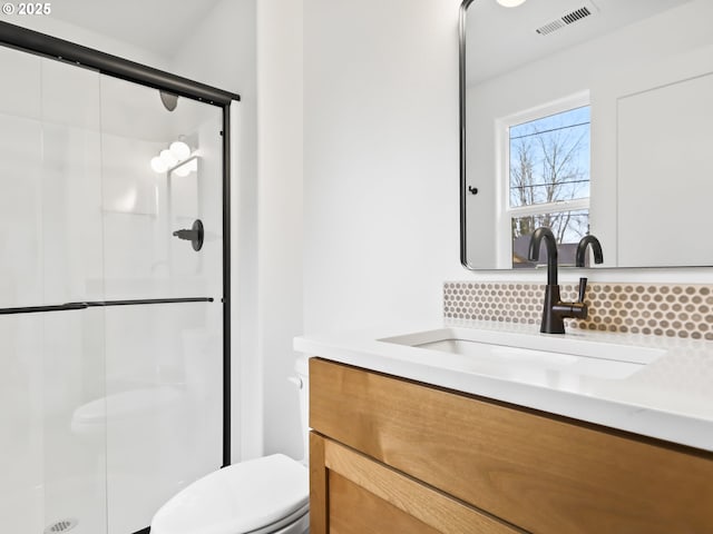 full bathroom with tasteful backsplash, visible vents, toilet, a stall shower, and vanity